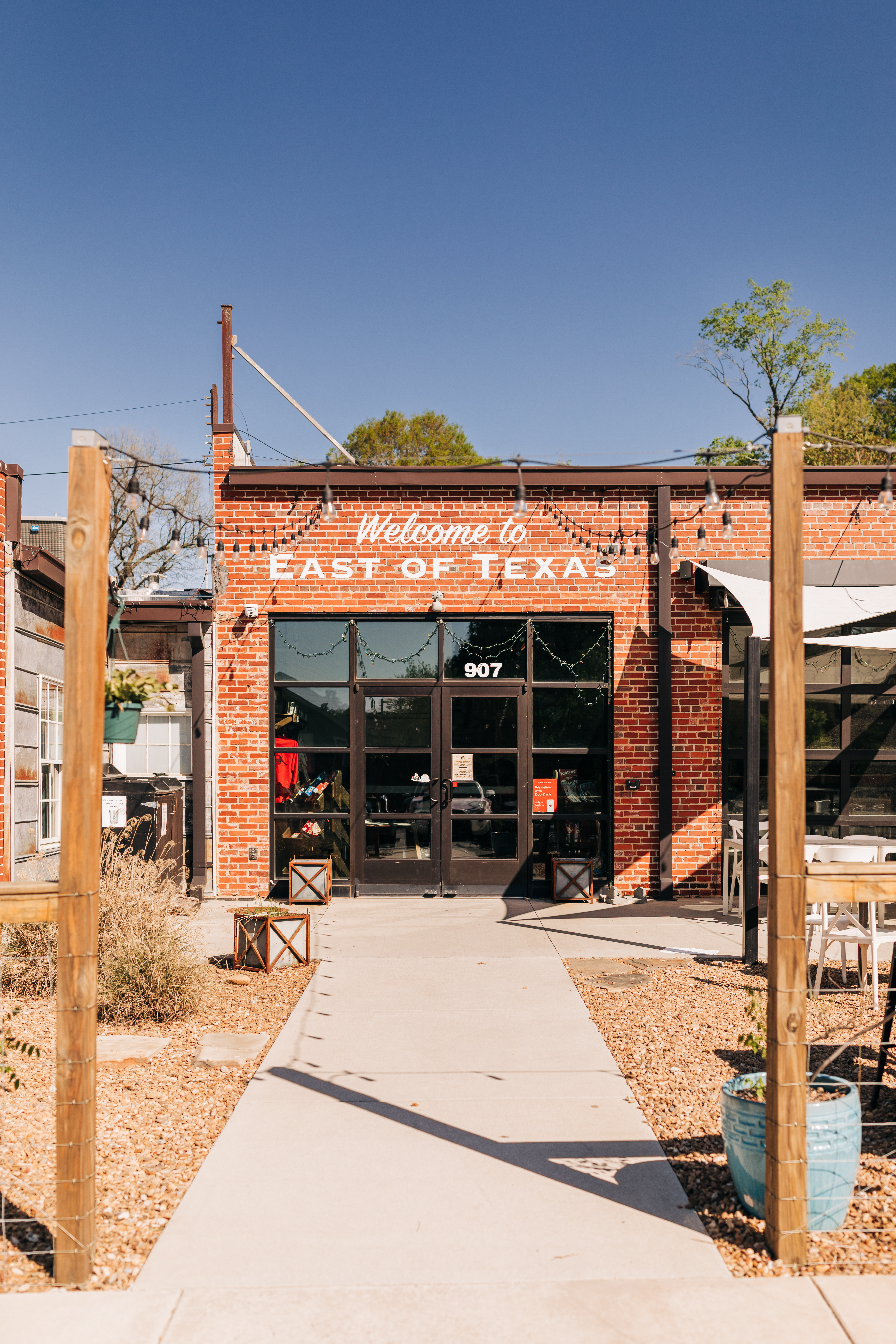 East of Texas restaurant entrance in Winston-Salem with brick exterior, patio seating, and string lights.